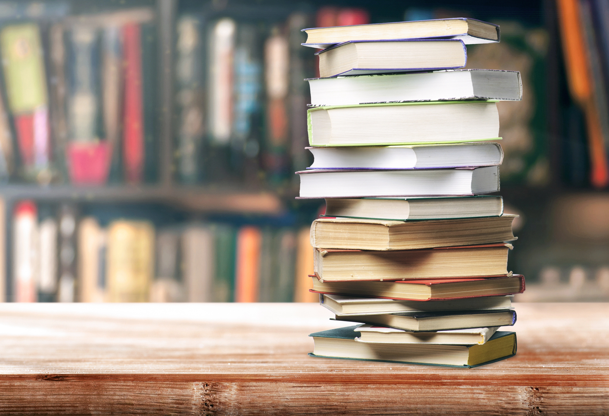 Stack of Books in front of bookshelves filled with books.