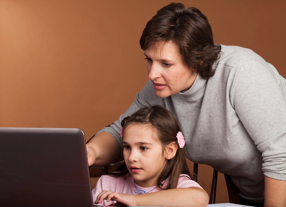 Mom helping child at computer.