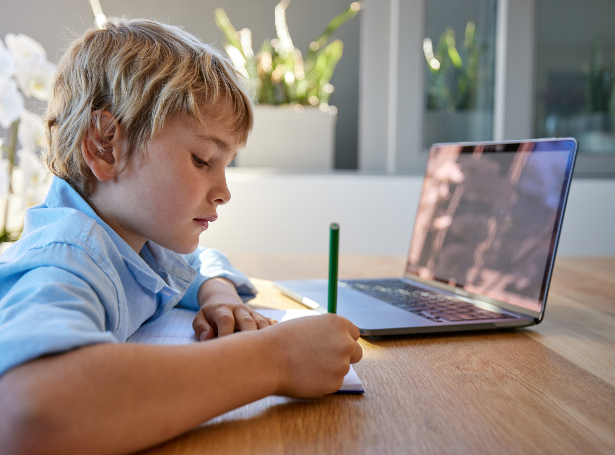 Young homeschool boy sitting alone and writing.
